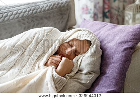 Sick Young Woman Slleping, Lying On Sofa, Wrapped In Wool White Plaid, Tries To Warm Herself, Having