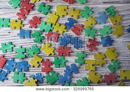 Colorful Puzzles On A White Wooden Background, Frame, Concept Of Early Childhood Autism