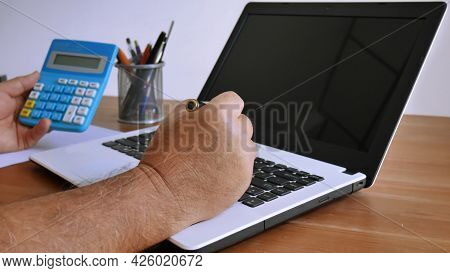 Man Working With Laptop While Using Calculater At Home, Work From Home Concept