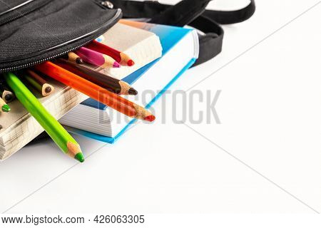 Open School Backpack On An White Background. Books, A Notebook And Pencils Are Sticking Out Of An Op