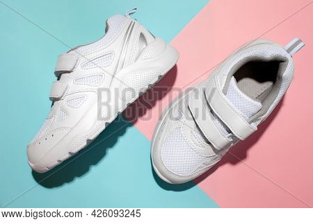 Top View Two White Sneakers On A Romantic Geometric Paper Pink And Blue Background With Hard Sunligh