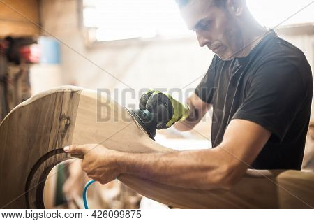 Craftsman Using Electric Sander, To Smoothen The Wood Texture