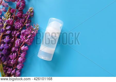 Unbranded Transparent Bottle Of Intimate Lubricant Gel And Purple Lupine Flower Frame. Intimate Mass