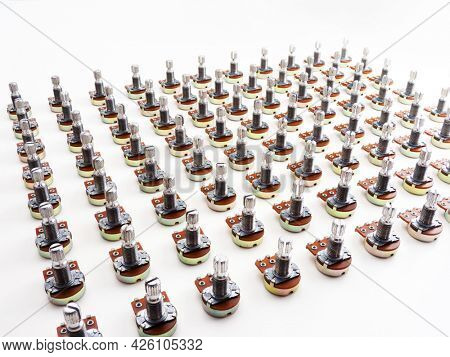 Electronic parts aligned. Many potention meters or variable resistors (also called volume pots) aligned on neutral white background.