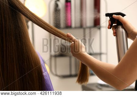 Professional Stylist Spraying Water Onto Client's Hair In Salon, Closeup