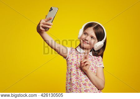 Young Charming Girl Kid In Colorful Polo Shirt Taking Selfie While Listening To Music In Headphones,