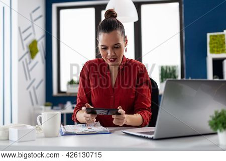 Businesswoman Sitting At Desk In Corporate Office Playing Video Games, Using Smartphone. Entrepeneur