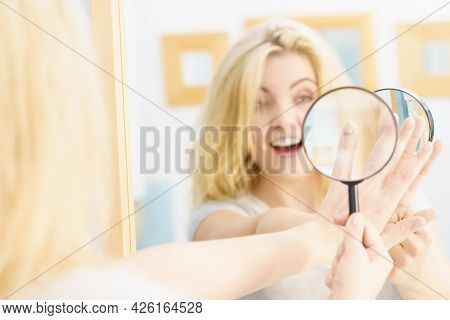 Beautiful Perfectionist Young Woman Checking Her Finger Nails Through Manifying Loupe Glass.