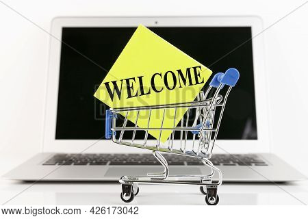 Shopping Cart, Laptop, Text, Welcome, On Yellow Paper. Business Concept. Copy Space
