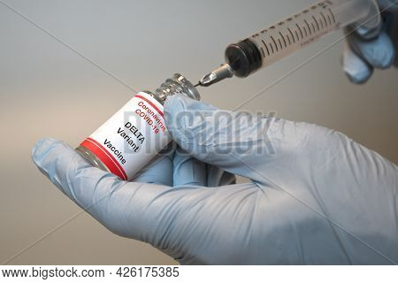 Covid-19 Delta Variant Vaccine. The Hand Of The Doctor With A Blue Glove Holds The Syringe And The H