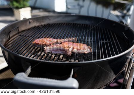 Pork Chop With Bones On On A Round Charcoal Grill. Close Up With Short Depth Of Field.