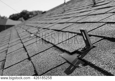 Residential Asphalt Shingle Roof With Metal Anchors Installed For The Installation Of A Solar Panel 