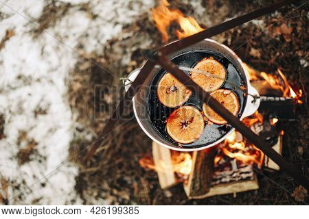 From Above Traditional Mulled Wine With Slices Of Orange Preparing In Pot Over Burning Logs In Winte