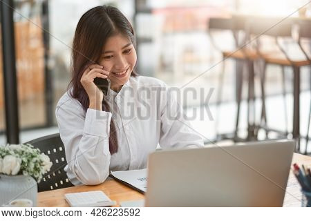 Young Businesswoman Speaking On The Phone Whilte Using Laptop Computer At Meeting Room. Business Tea