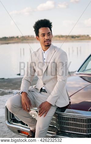 Young Black Man In Nature Posing With A Convertible. Sunset Portrait.