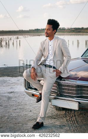 Young Black Man In Nature Posing With A Convertible. Sunset Portrait.