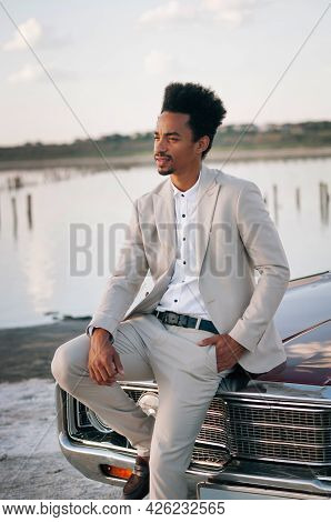 Young Black Man In Nature Posing With A Convertible. Sunset Portrait.