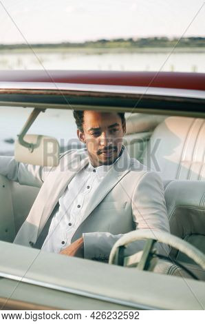 Young Black Man In Nature Posing With A Convertible. Sunset Portrait.