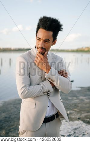 Young African American Man Pensively Looks To The Side At Sunset In Nature. Portrait Of The Groom.