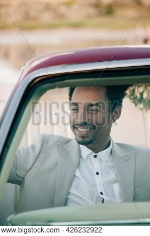 Young African American Man Groom In A Convertible Car At Sunset In Nature.