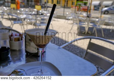 Ice Coffee, Cafe Shakerato In Glass Close-up On The Table Across Restaurant Furniture And City View.