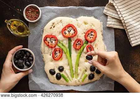 Female Hands Decorating Raw Focaccia With Vegetables And Herbs. Italian Cuisine, Garden Focaccia. To