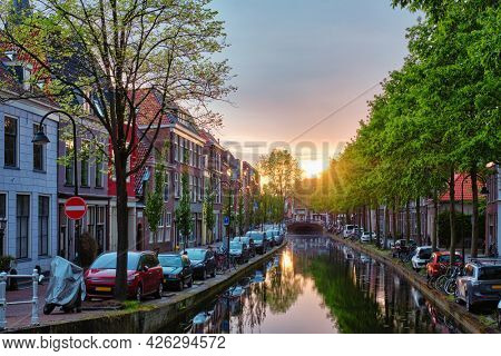 Delt canal with old houses and cars parked along on sunset. Delft, Netherlands