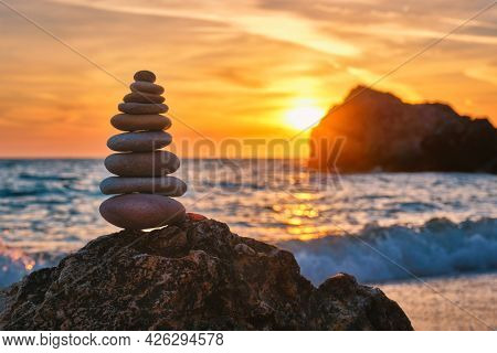 Concept of balance and harmony. Cairn stack of stones pebbles cairn on the beach coast of the sea in the nature on sunset. Meditative art of stone stacking