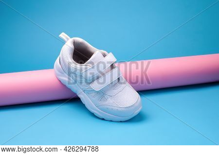 Balance One White Unisex Sneaker With Velcro Fasteners On A Pink Long Paper Tube On A Geometric Blue