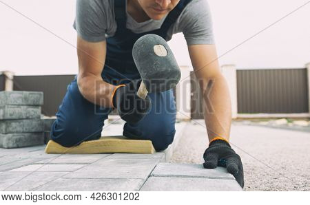 Worker lining paving slabs path