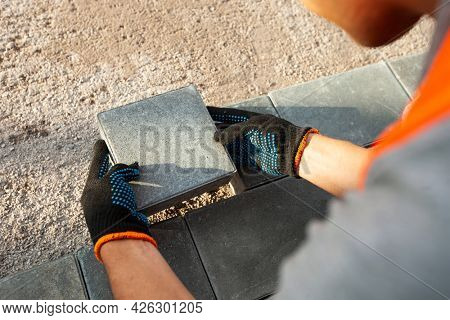 Worker lining paving slabs path