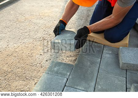 Worker lining paving slabs path