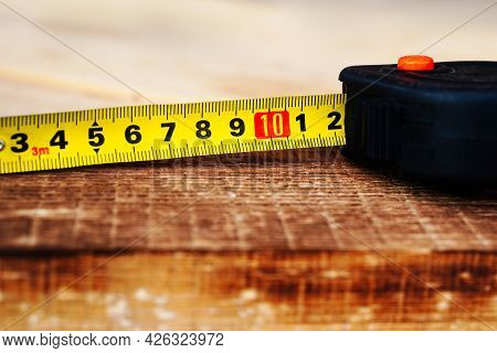 Unfolded Measuring Tape On A Wooden Board.