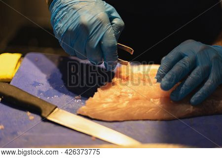 The Chef Cuts The Fish In Blue Gloves