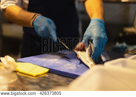 The Chef Cuts The Fish In Blue Gloves