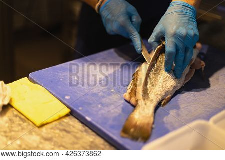 The Chef Cuts The Fish In Blue Gloves