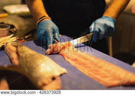 The Chef Cuts The Fish In Blue Gloves