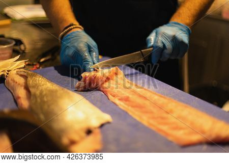The Chef Cuts The Fish In Blue Gloves