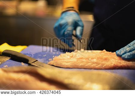 The Chef Cuts The Fish In Blue Gloves