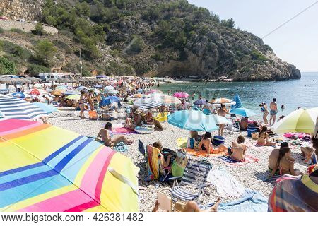 La Granadella  Spain - August 20 2016; Busy And Over-crowded Beach With Brightly Colored Sun Umbrell