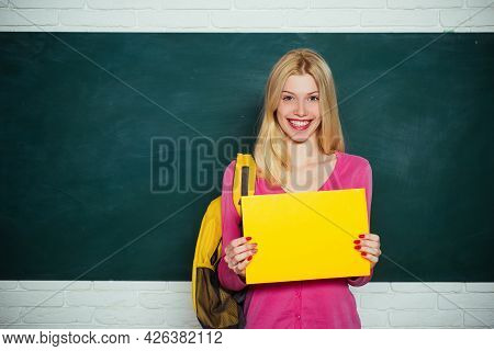 Student Girl Holding Empty Faper For Product. Learn With Fun. Funny Female Teacher Sitting At Her Wo