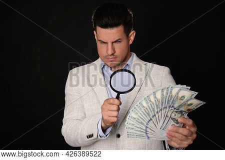 Expert Authenticating 100 Dollar Banknotes With Magnifying Glass Against Black Background. Fake Mone