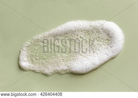 Face Cleansing Mousse Sample. White Cleanser Foam Bubbles On Green Background. Soap, Shower Gel, Sha