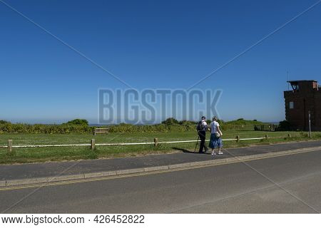 Old Hunstanton, Norfolk, England - June 13 2021. Elderly Couple Walking Hand In Hand On Their Back O