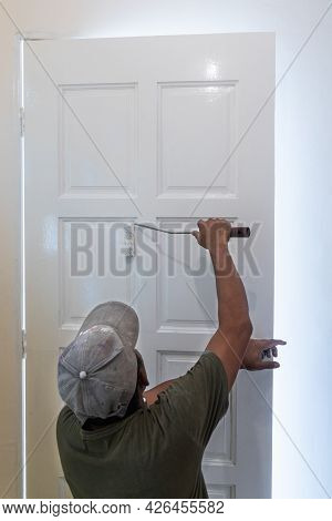 Person Painting Wooden White Door With Paint Roller During Home Rennovation