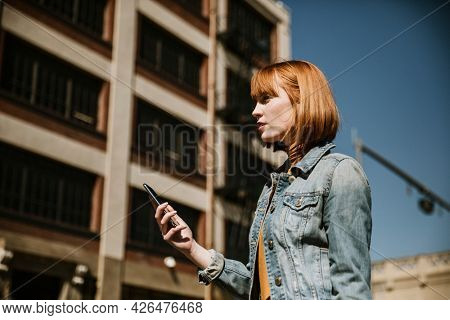 Woman standing on a streetside with her phone