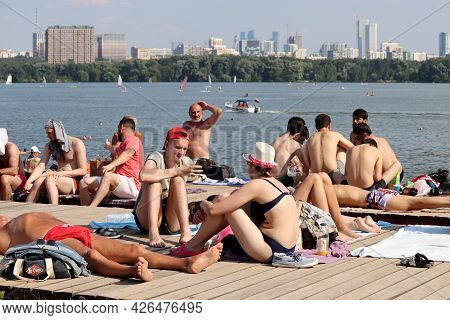 Moscow, Russia - July 2021: People Tanning On Wooden Flooring Of Beach Of Moscow River In Strogino O
