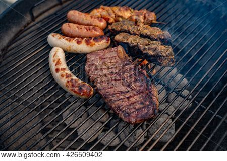 Spicy Marinated Meat On Round Charcoal Grill. Close Up With Short Depth Of Field. Barbecue Meat.