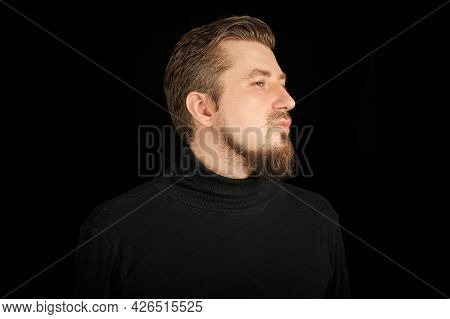 Cute Bearded Man, Half-face Portrait, Black Background. Young Guy In Black Polo Neck Sweater. Confid