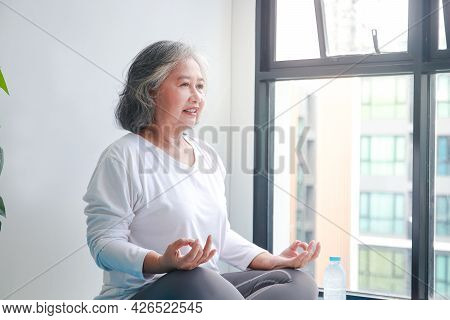 Asian Elderly Woman Sitting At Home Exercising, Doing Yoga Poses. Social Distancing, Exercise To Mai